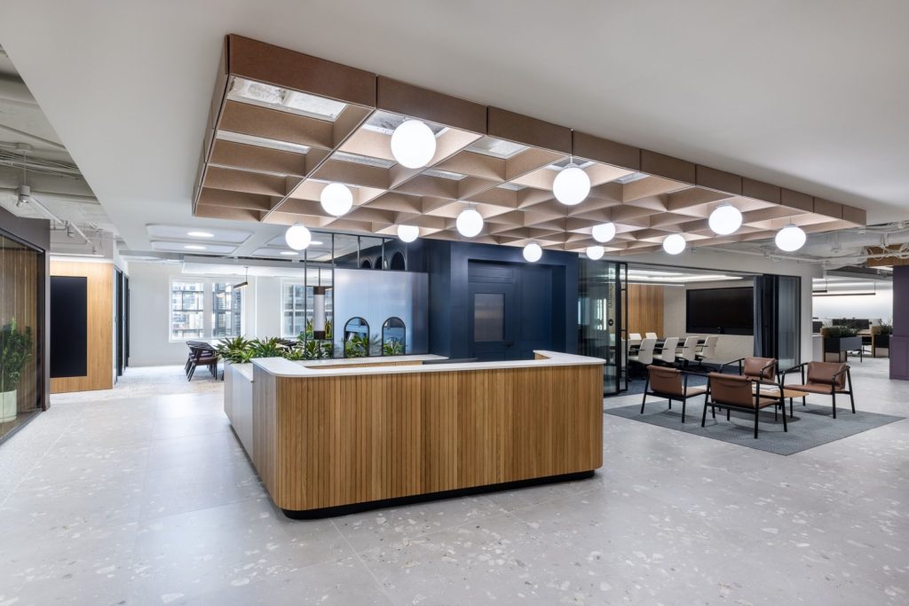 Rendering of an interior office space with an open concept and central, wooden reception desk.