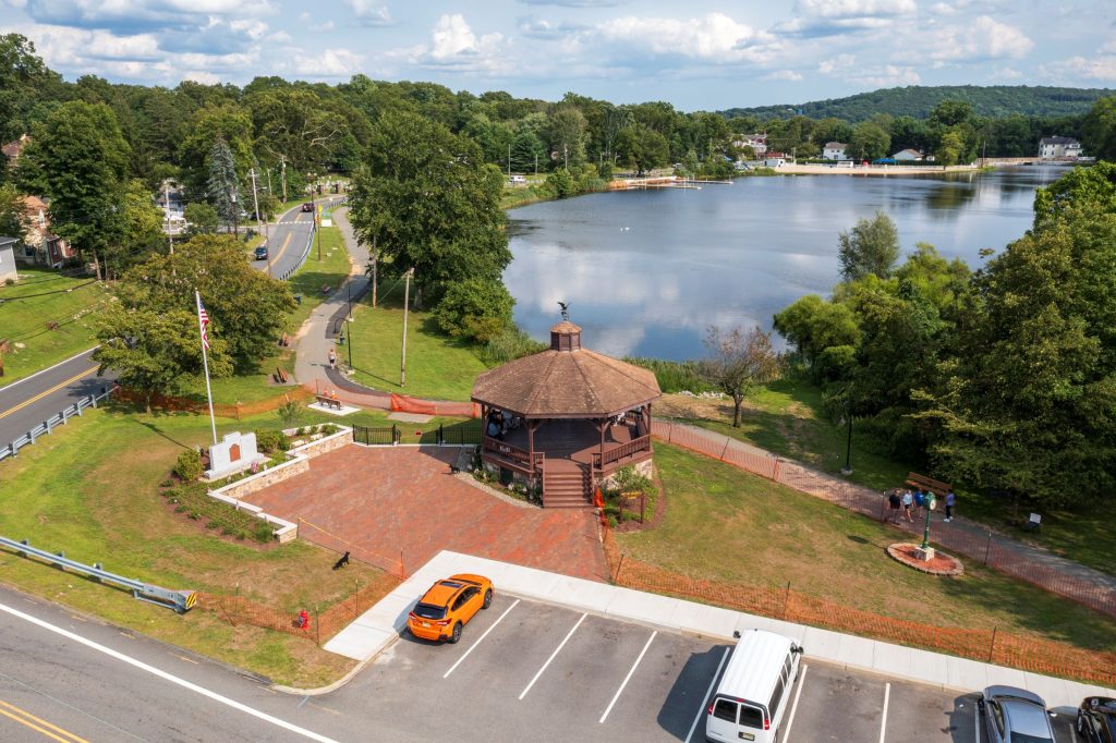 Park with gazebo surrounded by a body of water and lush, green trees