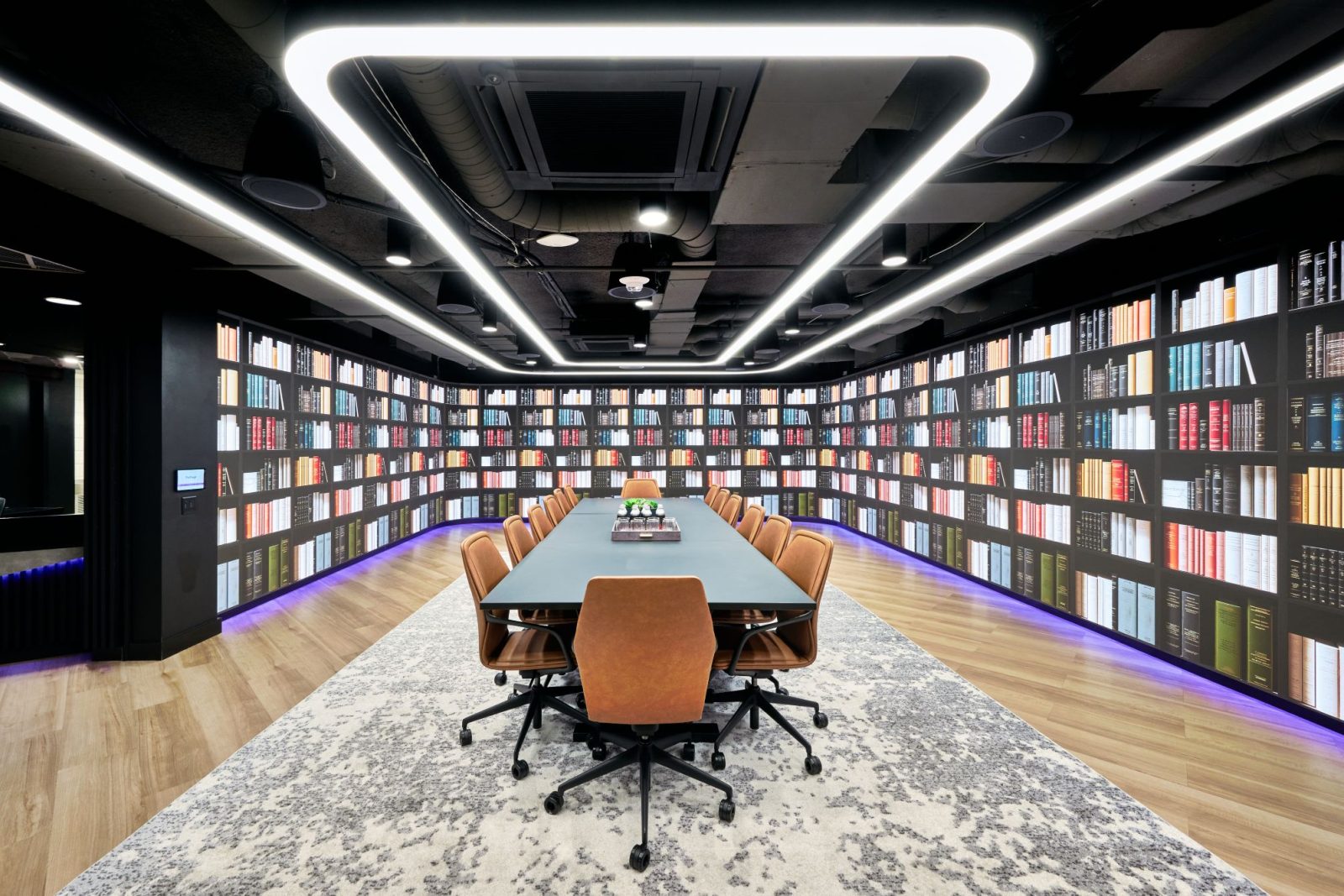 Conference room featuring a large table, chairs, and bookshelves filled with books along the walls.